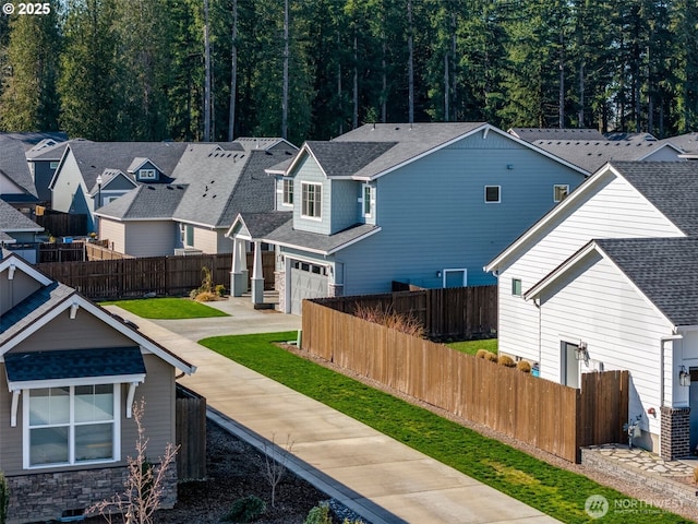 exterior space featuring a fenced front yard, a garage, and roof with shingles