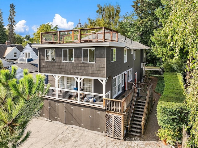 rear view of property with stairs and a balcony