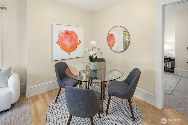 dining space with baseboards and wood finished floors