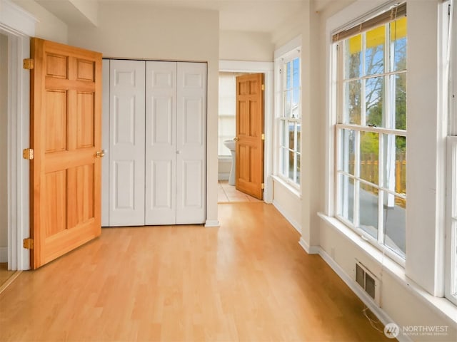 interior space with a closet, visible vents, light wood-style flooring, and baseboards