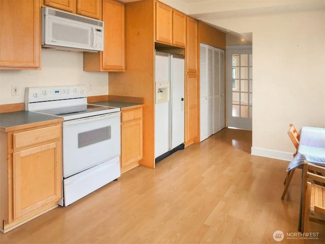 kitchen with white appliances, baseboards, light brown cabinetry, dark countertops, and light wood-type flooring