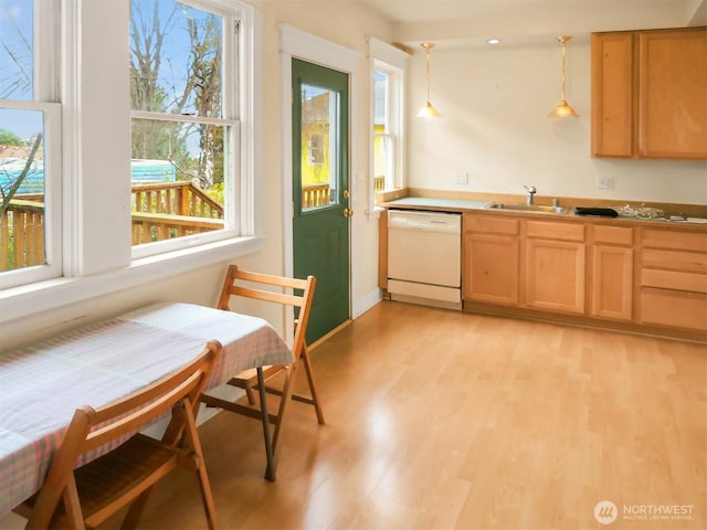 kitchen with light brown cabinets, decorative light fixtures, light wood-style flooring, white dishwasher, and a sink