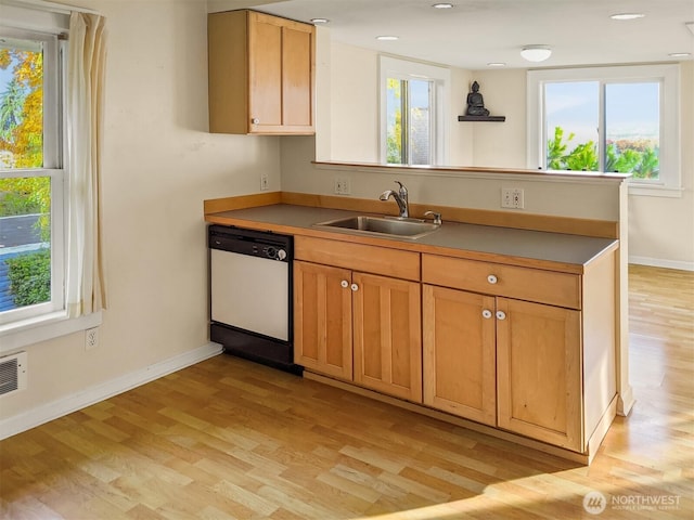 kitchen featuring baseboards, dishwasher, light wood-style flooring, a peninsula, and a sink