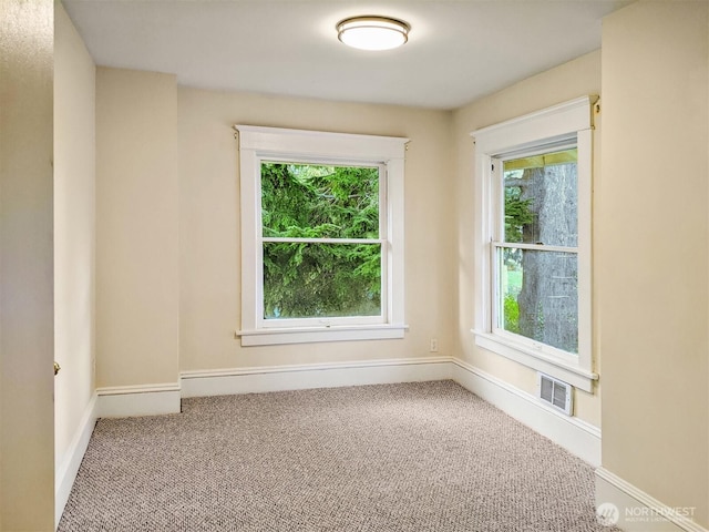 carpeted empty room featuring visible vents and baseboards