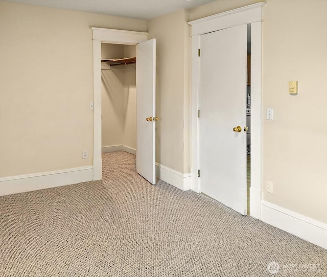 unfurnished bedroom with a walk in closet, carpet flooring, baseboards, and a closet