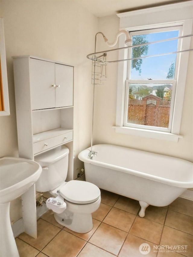 bathroom featuring tile patterned flooring, toilet, and a freestanding bath