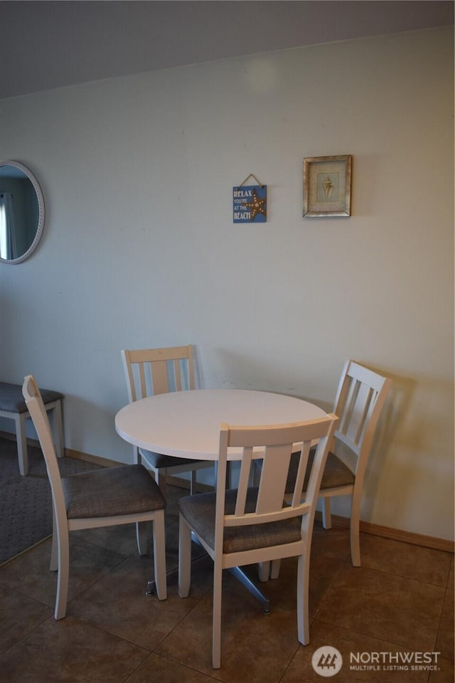 tiled dining space featuring baseboards