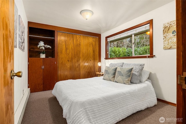 carpeted bedroom featuring a baseboard radiator, baseboards, and a closet