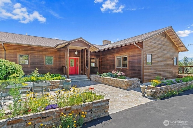 rustic home with roof with shingles and a chimney