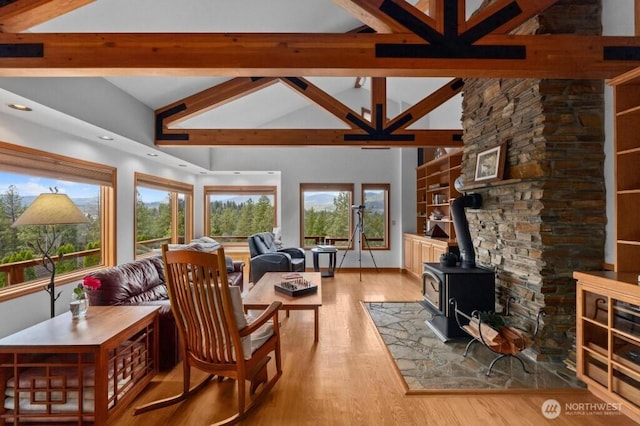 living room with a wealth of natural light, light wood-type flooring, beam ceiling, and a wood stove