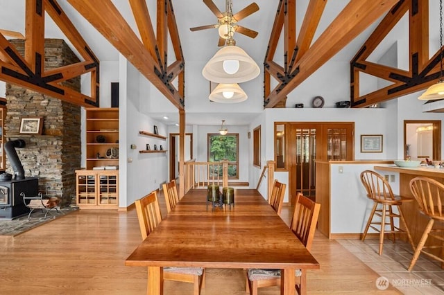 dining area featuring a ceiling fan, a wood stove, and wood finished floors