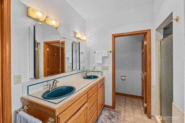 bathroom featuring double vanity, tile patterned flooring, baseboards, and a sink