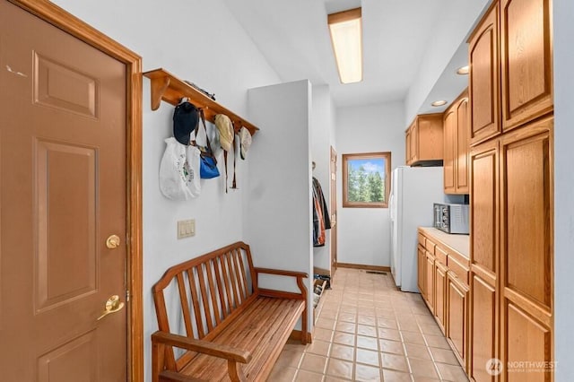 interior space featuring stainless steel microwave, baseboards, light countertops, freestanding refrigerator, and light tile patterned flooring