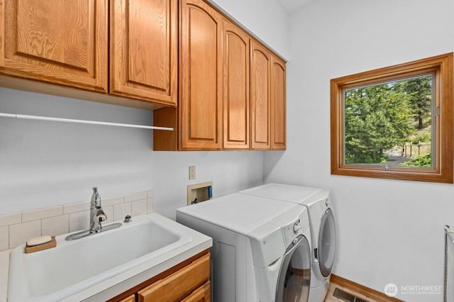 laundry room with visible vents, a sink, cabinet space, baseboards, and washing machine and clothes dryer