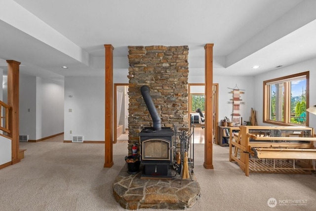 carpeted living room featuring recessed lighting, visible vents, baseboards, and a wood stove