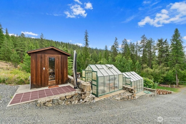 view of greenhouse featuring a view of trees