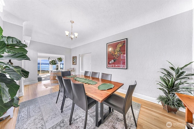 307 W Highland Dr, Seattle, WA 98119 - dining room with wood finished floors, a notable chandelier, a textured wall, and baseboards