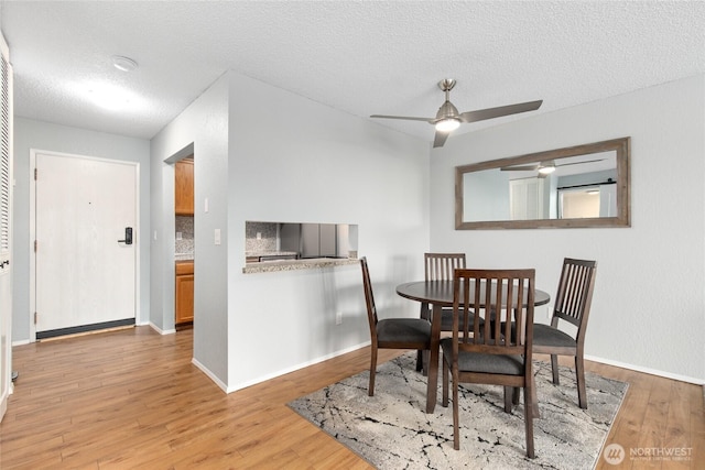 dining space with baseboards, a textured ceiling, a ceiling fan, and light wood finished floors