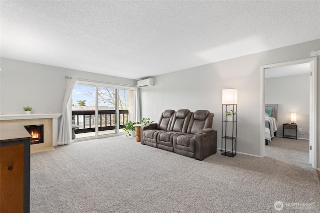 carpeted living area featuring baseboards, a fireplace with flush hearth, a textured ceiling, and a wall unit AC