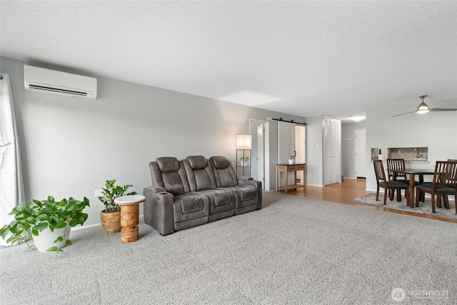 living area featuring a textured ceiling, an AC wall unit, carpet, and a barn door