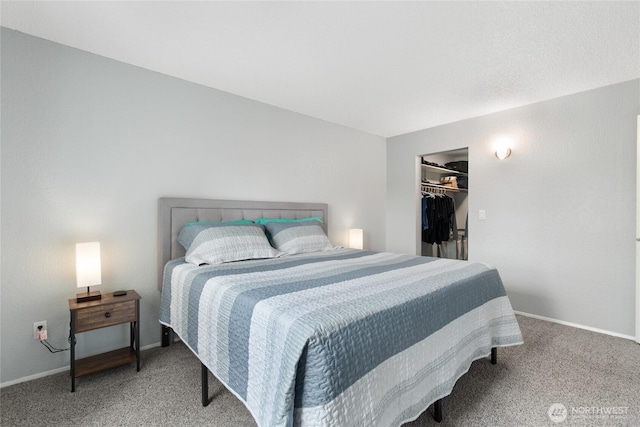 bedroom with a closet, a spacious closet, baseboards, and carpet