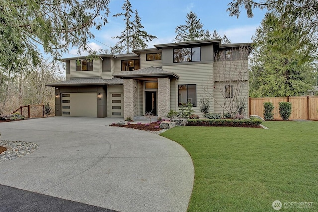 prairie-style house featuring an attached garage, concrete driveway, a front yard, and fence