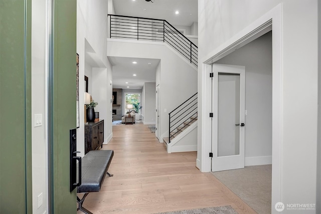 foyer featuring stairway, recessed lighting, light wood-style flooring, and a high ceiling