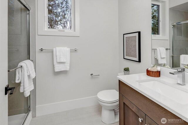 bathroom with vanity, a shower stall, a healthy amount of sunlight, and baseboards