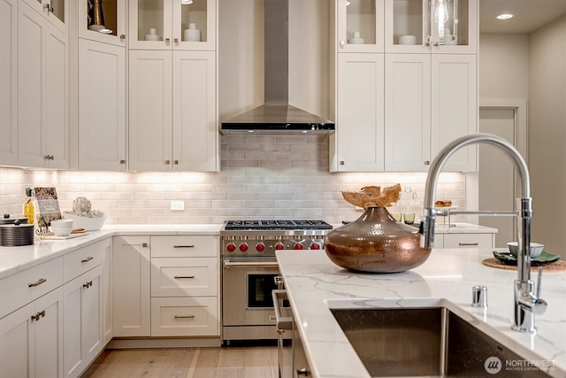 kitchen with white cabinetry, wall chimney exhaust hood, and luxury stove