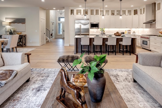 living area featuring baseboards, stairs, recessed lighting, an inviting chandelier, and light wood-style floors