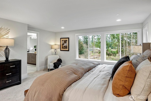 bedroom with recessed lighting, baseboards, ensuite bathroom, and light carpet