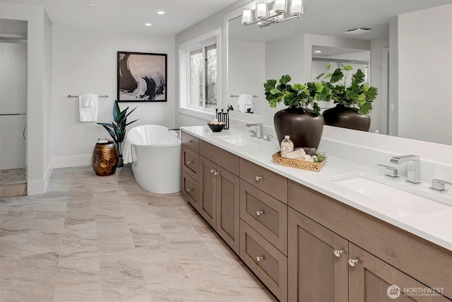 bathroom with a shower stall, a freestanding bath, and a sink