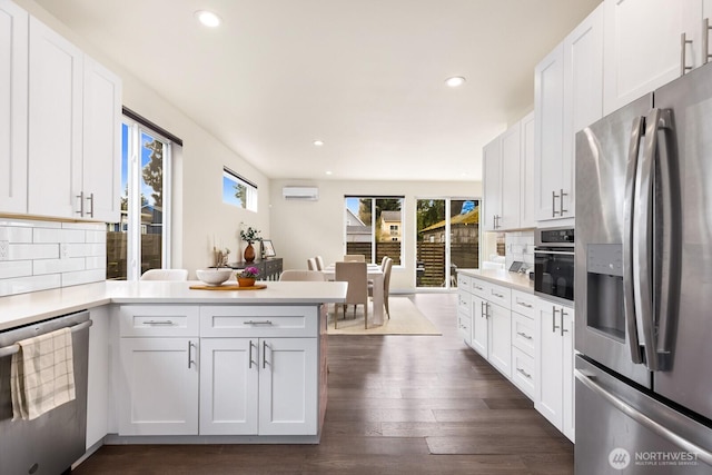 kitchen featuring a peninsula, light countertops, dark wood-type flooring, and appliances with stainless steel finishes