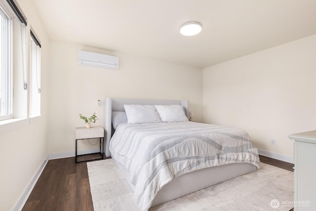 bedroom with a wall unit AC, wood finished floors, and baseboards