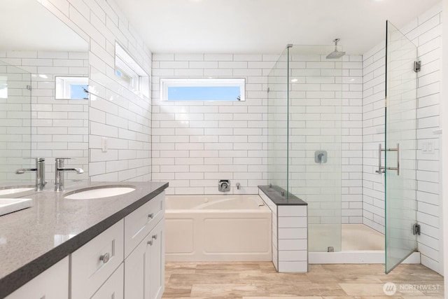 bathroom featuring wood finished floors, a garden tub, a stall shower, and vanity