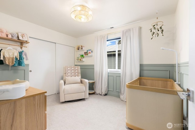 bedroom featuring light carpet, visible vents, wainscoting, and a closet