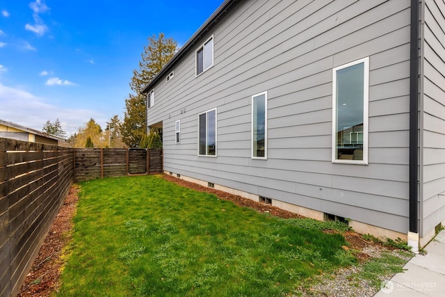 view of side of property featuring a lawn and a fenced backyard