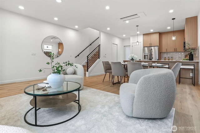 living area with visible vents, baseboards, stairs, recessed lighting, and light wood-style floors