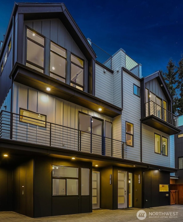 back of house at night featuring board and batten siding