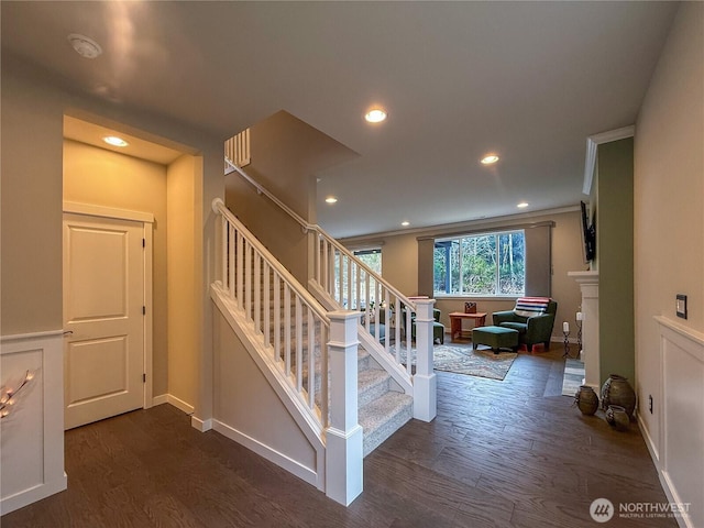 staircase with baseboards, ornamental molding, recessed lighting, a fireplace, and wood finished floors