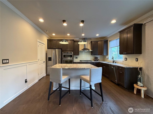 kitchen featuring stainless steel appliances, a kitchen breakfast bar, dark brown cabinetry, and wall chimney range hood