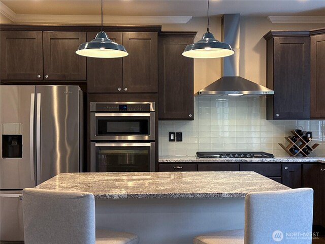 kitchen featuring ornamental molding, backsplash, dark brown cabinetry, appliances with stainless steel finishes, and wall chimney range hood