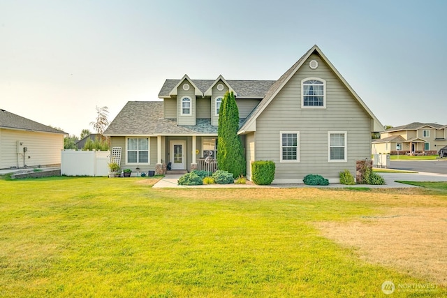 view of front of home featuring a front lawn, fence, and roof with shingles