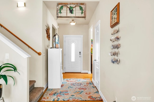 entrance foyer with stairway, baseboards, and light wood-style flooring