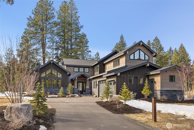 view of front of property featuring stone siding, board and batten siding, concrete driveway, and an attached garage