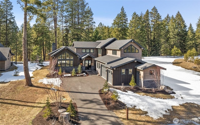 view of front of property with a garage, board and batten siding, concrete driveway, and a wooded view