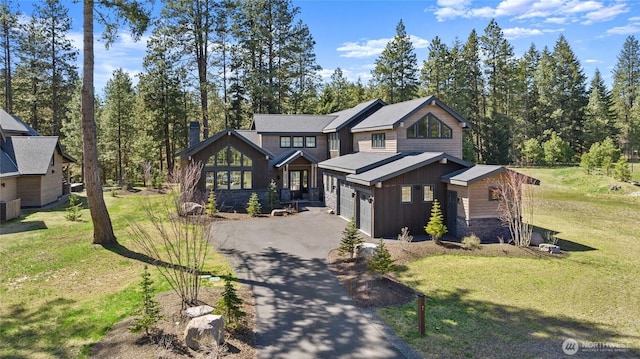 view of front facade featuring a front lawn, driveway, stone siding, and board and batten siding
