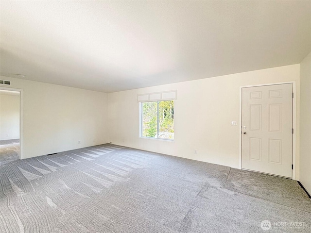 carpeted empty room featuring visible vents