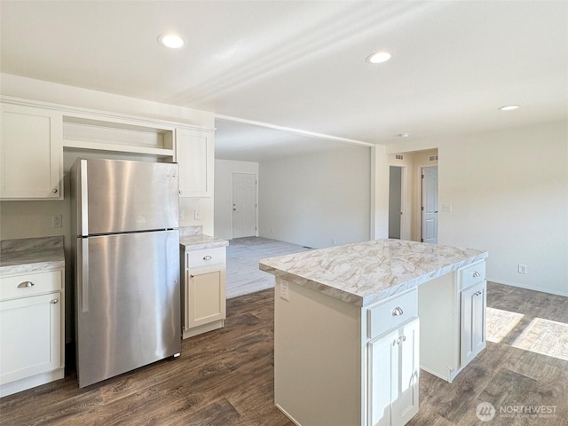 kitchen featuring a kitchen island, dark wood finished floors, open shelves, freestanding refrigerator, and light countertops