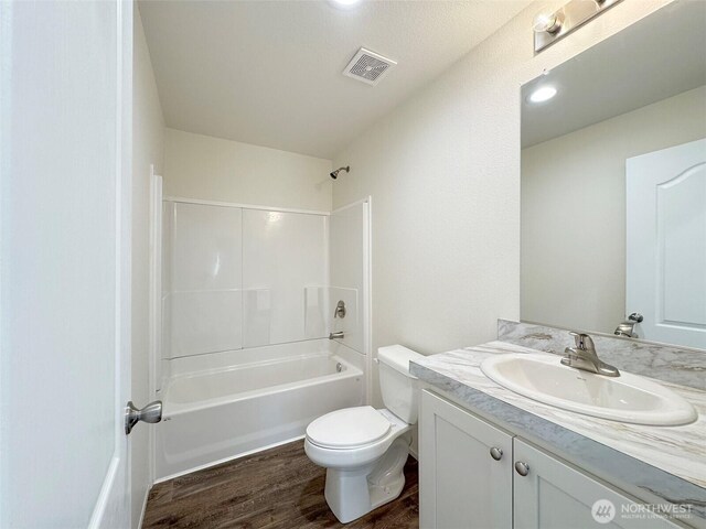 bathroom featuring visible vents, toilet, wood finished floors, bathtub / shower combination, and vanity